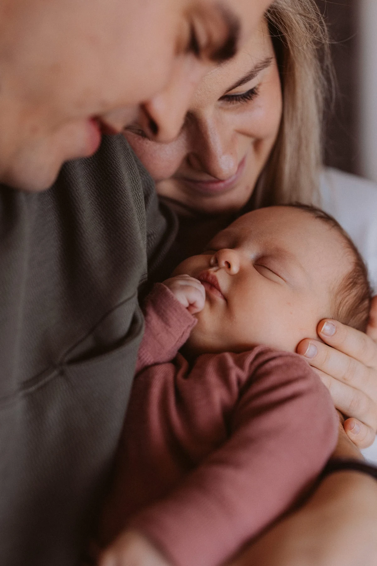 Eltern kuscheln zuhause mit ihrem schlafenden Neugeborenen